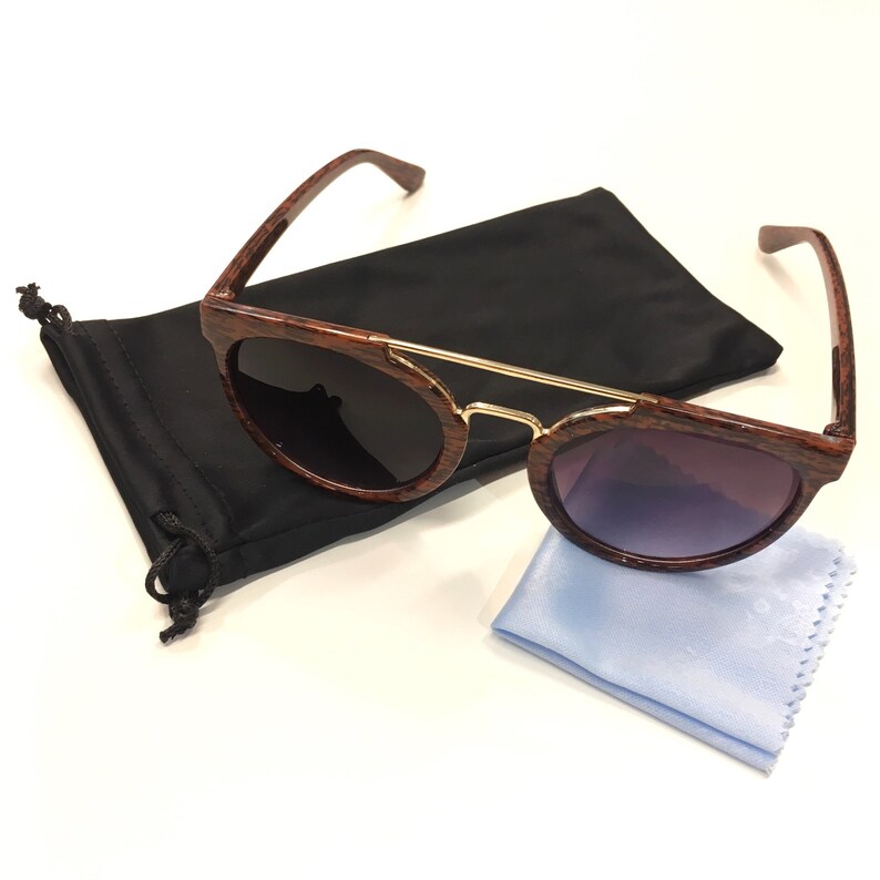 May include: Brown wood-grain sunglasses with gold accents and a black microfiber pouch and cleaning cloth.