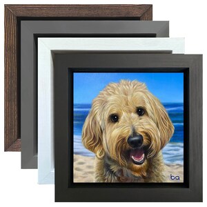 Puede incluir: Una pintura enmarcada de un perro dorado con una expresión feliz. El perro está sentado en una playa con agua azul y olas blancas en el fondo. La pintura está enmarcada en un marco de madera marrón oscuro con un paspartú blanco.