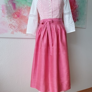 May include: A pink dirndl with a white and pink gingham bodice and a white blouse with lace trim.
