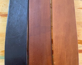 May include: Three leather straps in different shades of brown, black, and a lighter brown. The straps are all the same width and length.