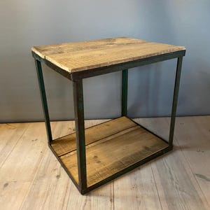 Könnte beinhalten: Ein kleiner, quadratischer Beistelltisch im Industriestil mit einem grünen Metallrahmen und zwei Holzböden. Der Tisch ist aus recyceltem Holz gefertigt und hat einen rustikalen, Vintage-Look.