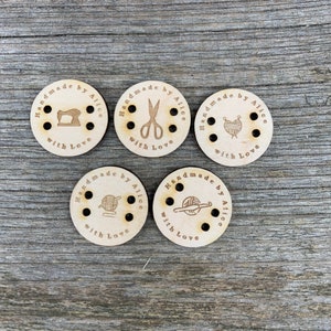 May include: Five wooden round tags with holes and a brown design. Each tag says "Handmade by Alice with Love" and features a different icon: a sewing machine, scissors, yarn and needles, yarn and crochet hook, and yarn and knitting needles.
