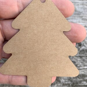 K&ouml;nnte beinhalten: Ein braunes Papier-Weihnachtsbaum-Etikett mit einem Loch oben.