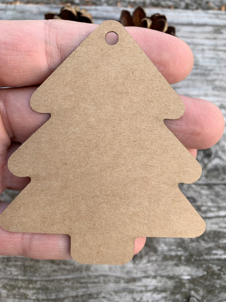 K&ouml;nnte beinhalten: Ein braunes Papier-Weihnachtsbaum-Etikett mit einem Loch oben.