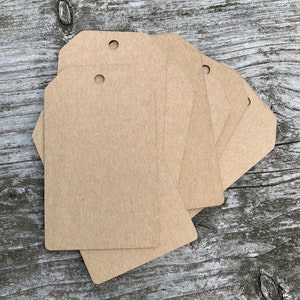 Pode incluir: Um conjunto de seis etiquetas de presente de papel kraft castanho com um furo perfurado no topo. As etiquetas est&atilde;o em branco e prontas para serem escritas.