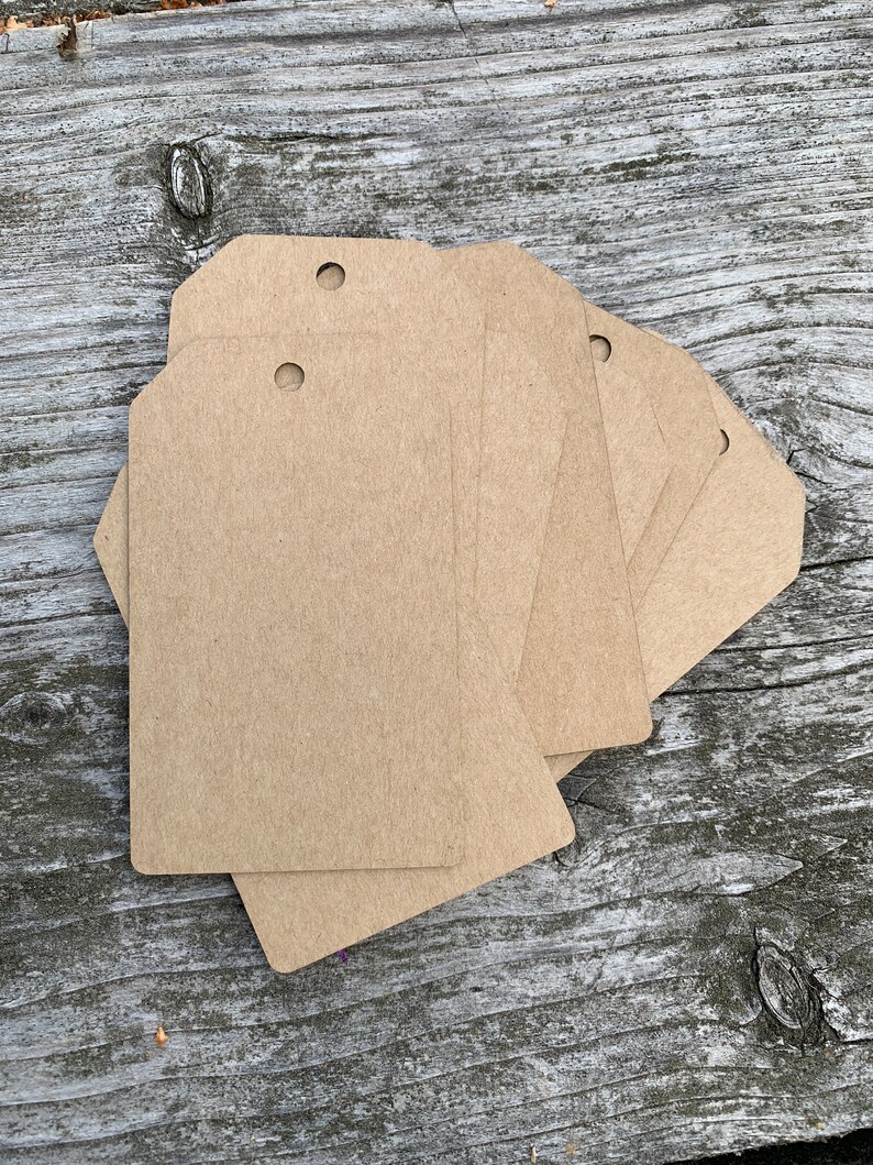 Pode incluir: Um conjunto de seis etiquetas de presente de papel kraft castanho com um furo perfurado no topo. As etiquetas est&atilde;o em branco e prontas para serem escritas.