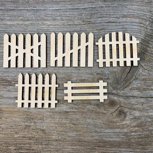 Può includere: Cinque sagome di recinzione in legno in vari stili, tra cui un cancello, su uno sfondo in legno grigio.