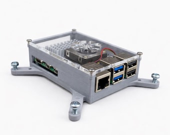 May include: A gray, rectangular computer case with a clear top, featuring a small fan and various ports. The case is secured with screws and has extended mounting feet. The design is for a small computer or electronic device.