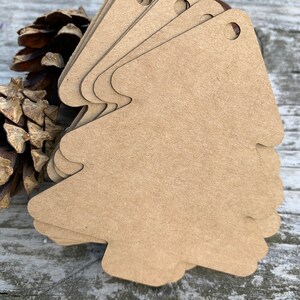 K&ouml;nnte beinhalten: Ein Stapel brauner Papier-Geschenk-Anh&auml;nger in Weihnachtsbaumform mit einem Loch oben.