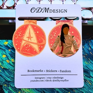 May include: Two bookmarks featuring a Starfleet emblem and a character illustration. The bookmarks are circular with a red and orange color scheme. The text "ODMdesign" is at the top, and "Bookmarks • Stickers • Fandom" is at the bottom.