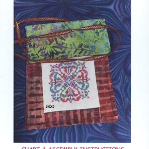 May include: A cross stitch pattern for a cell phone bag with a red, green, and purple floral design. The pattern is called "Quicky Zippy Cell Phone Bag" and is labeled B-007. The pattern is from Rosewood Manor.