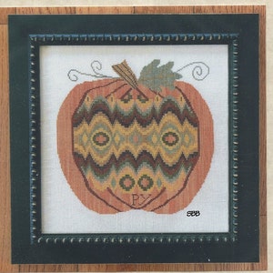 May include: A framed cross-stitch pattern of a pumpkin with a bargello design. The pumpkin is orange with brown, yellow, and green accents. The frame is brown with a black mat. The text "Great Pumpkin Bargello" is at the top of the image. The text "Samplers Revisited" is at the bottom of the image.