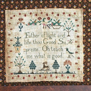 May include: Two framed cross-stitch embroidery pieces with a white background and colourful thread. The embroidery features a floral design with a deer and trees. The text reads "Father of light and life thou Good Supreme. Oh teach me what is good."