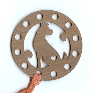 May include: A wooden embroidery floss organizer with a silhouette of a dog and a heart. The organizer has 12 holes around the edge and a tassel attached to the bottom.