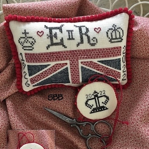 Może przedstawiać: Trzy haftowane ozdoby z motywem czerwono-biało-niebieskiej flagi Unii. Ozdoby przedstawiają tekst "ER II" oraz lata "1926", "2022" i "2022".