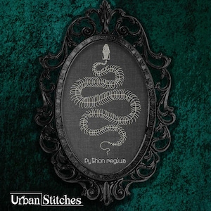 May include: A black ornate frame with a white embroidered image of a snake with the text "python regius" underneath.