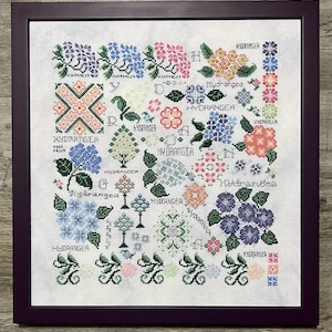 Könnte beinhalten: Kreuzstich-Stickerei mit verschiedenen Hortensienblüten-Designs in Blau, Rosa und Grün, mit dem Wort "HYDRANGEA" wiederholt. Das Kunstwerk ist in einem dunkelvioletten Holzrahmen gerahmt.