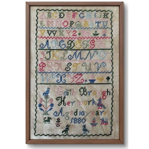 May include: Framed antique sampler with colorful cross-stitch letters, numbers, and decorative motifs. The sampler includes the text "Edith Brough Her work Aged 10 years 1880" in a wooden frame.