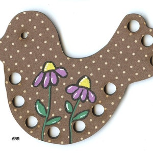 May include: Brown wooden bird-shaped yarn holder with purple and yellow flowers painted on it. The bird has eight holes for yarn.