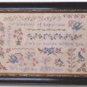 May include: A framed cross-stitch sampler featuring a bluebird design and the text "Bluebird of happiness always reside within you. Wrought by J.O.W. 2002".