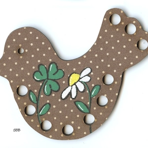 May include: Brown wooden bird-shaped yarn holder with white polka dots and painted green clover and white daisy flowers. The holder has eight holes for yarn.