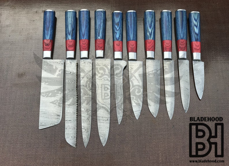 Puede incluir: Un juego de diez cuchillos de cocina con hojas y mangos estampados. Los mangos son azules y rojos con una virola plateada. Las hojas tienen un dise&ntilde;o grabado &uacute;nico. El logotipo "BLADEHOOD" es visible en la esquina inferior derecha.