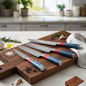 Puede incluir: Cuatro cuchillos de cocina con hojas estampadas y mangos azules y rojos descansan sobre una tabla de cortar de madera. Los cuchillos est&aacute;n colocados en la tabla con una etiqueta que dice "Handcrafted in USA". La tabla de cortar es marr&oacute;n y tiene un asa.