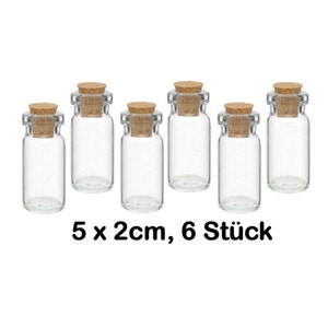 Könnte beinhalten: Sechs klare Glasflaschen mit Korkstopfen. Jede Flasche ist etwa 5 Zentimeter hoch. Die Flaschen sind in zwei Reihen zu je drei angeordnet. Der Text "5 x 2cm, 6 Stück" ist unter den Flaschen gedruckt.