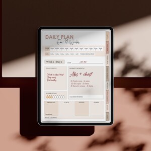 May include: A digital tablet displaying a daily plan for 12 weeks. The screen shows a workout schedule for week 1, day 1, focusing on abs and chest. The workout includes 6 push ups, 10 sit ups, and 3 bench presses. The tablet also includes sections for water intake, calories burned, and meal planning.