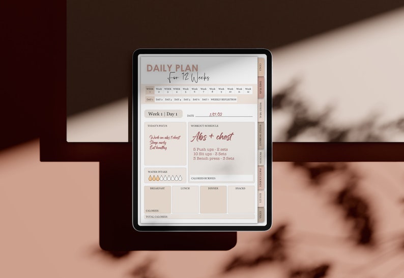 May include: A digital tablet displaying a daily plan for 12 weeks. The screen shows a workout schedule for week 1, day 1, focusing on abs and chest. The workout includes 6 push ups, 10 sit ups, and 3 bench presses. The tablet also includes sections for water intake, calories burned, and meal planning.