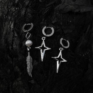 May include: Three silver earrings with different charms. One earring has a pearl and a feather charm, another has a star charm, and the third has a star charm with a cutout design.