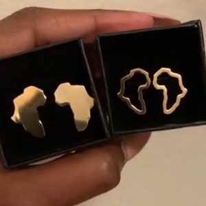 Puede incluir: Dos pares de pendientes de oro en forma del continente africano. Un par es de oro macizo, y el otro par es un contorno del continente.