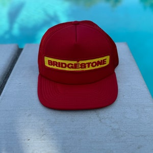 Vintage Bridgestone Tires Logo Patch on a Flat Brimmed Red Trucker Hat