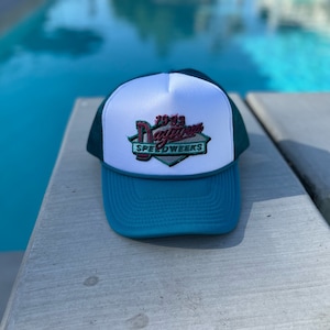 May include: A teal and white trucker hat with a red and white embroidered patch that says "70-93 Daytona Speedweeks".