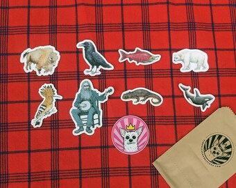May include: A set of colorful stickers featuring various animals, including a bison, a raven, a salmon, a polar bear, a hoopoe, a banjo player, a lizard, a whale, and a chihuahua. The stickers are on a red and black plaid background.