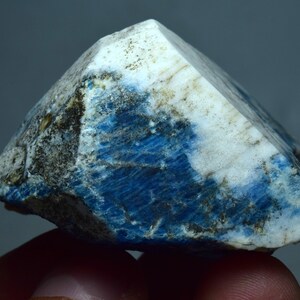 May include: A rough, blue and white mineral specimen with a crystalline structure. The mineral has a dark blue color with white streaks and a rough, uneven surface.