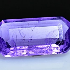 May include: A purple amethyst gemstone with a rectangular emerald cut.