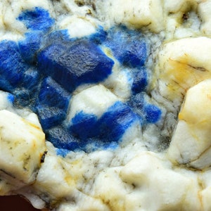 May include: Close-up of a white and blue mineral specimen with a rough, textured surface. The blue areas are irregularly shaped and appear to be embedded in the white rock.