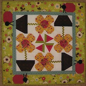 May include: A white background with a green border featuring a floral pattern. The center of the quilt block features four yellow flowers with brown pots and green stems. The flowers are surrounded by four watermelon slices.