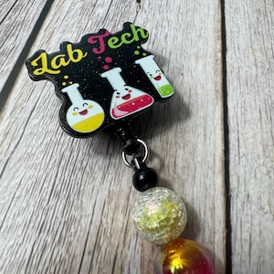 May include: A black and white badge holder with the text "Lab Tech" and three cartoon beakers with smiling faces. The badge holder is attached to a beaded lanyard with white, yellow, orange, and pink beads.