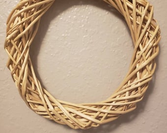 May include: A natural woven wreath made of light brown twigs, perfect for decorating a door or wall.