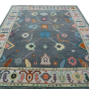 Hand-knotted wool rug in floral Turkish Oushak style, 8x10; blue-gray field with teal, rust, and peach blossoms.
