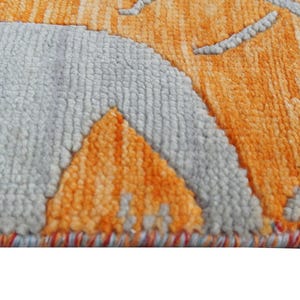 Hand-knotted wool Oushak rug in paisley pattern; rolled samples in teal, blue, orange for a textured floor decor rug.