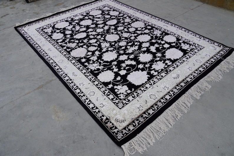 A 5.5x7.9 ft hand-knotted rug featuring a large, ornate ivory and blue central medallion on a deep navy blue field. The field is filled with intricate scrolling vines and small floral motifs. A wide, multi-layered border in ivory and light blue frames the rug. The rug is made of wool with silk highlights that give it a subtle sheen, finished with a short white fringe at the top and bottom.