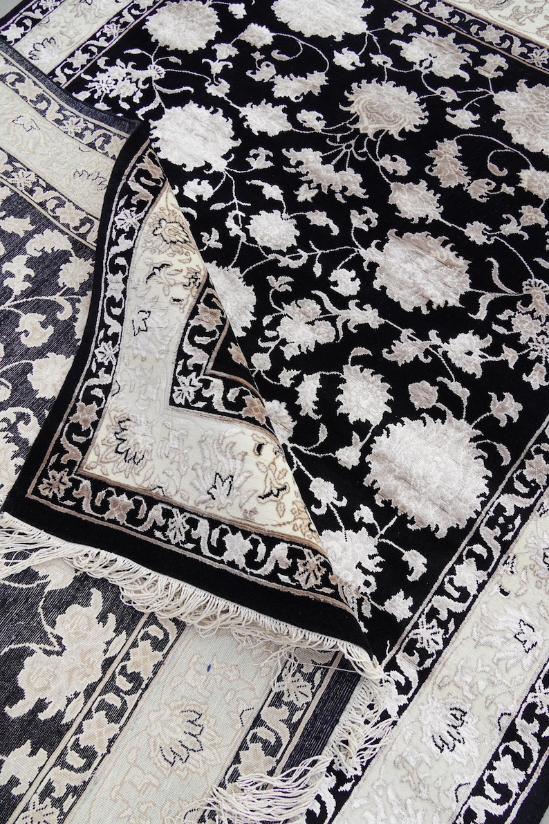 A 5.5x7.9 ft hand-knotted rug featuring a large, ornate ivory and blue central medallion on a deep navy blue field. The field is filled with intricate scrolling vines and small floral motifs. A wide, multi-layered border in ivory and light blue frames the rug. The rug is made of wool with silk highlights that give it a subtle sheen, finished with a short white fringe at the top and bottom.
