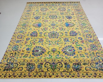 Könnte beinhalten: Ein großer, rechteckiger gelber Teppich mit einem komplizierten Blumenmuster. Der Teppich hat ein zentrales Medaillon-Design mit blauen, grünen und violetten Blumenmotiven. Der Rand ist ein dunklerer Gelbton mit ähnlichen floralen Details.