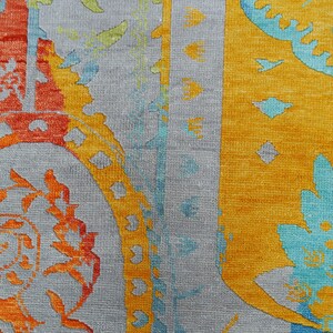 Hand-knotted wool Oushak rug in paisley pattern; rolled samples in teal, blue, orange for a textured floor decor rug.