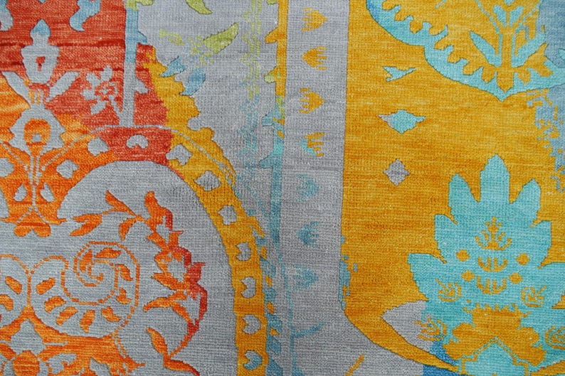 Hand-knotted wool Oushak rug in paisley pattern; rolled samples in teal, blue, orange for a textured floor decor rug.