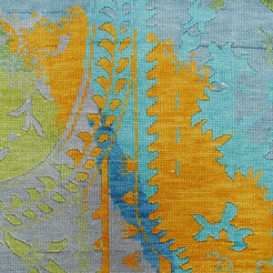Hand-knotted wool Oushak rug in paisley pattern; rolled samples in teal, blue, orange for a textured floor decor rug.