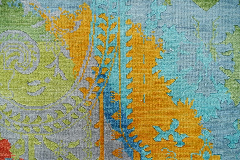 Hand-knotted wool Oushak rug in paisley pattern; rolled samples in teal, blue, orange for a textured floor decor rug.